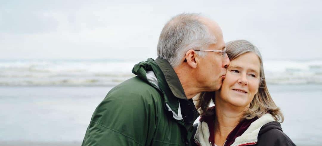 An older couple kissing on the beach