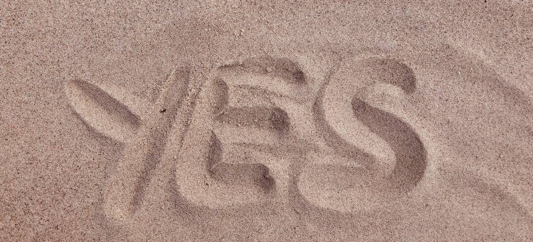 The word yes is written in the sand.